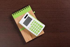 notebook on a brown wooden background with a calculator and magnifying glass photo