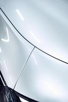 Sleek white car body with smooth curves and polished finish in a well-lit garage setting photo