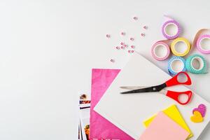 Creative crafting setup with scissors, colored paper, and decorative tape on a white background photo