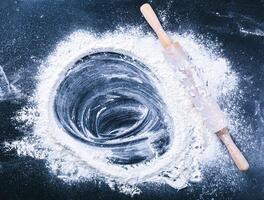 Baking desk with flour and rolling pin, top view photo