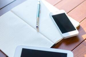 Notebooks and smartphones arranged on a wooden table for planning or brainstorming work in a cozy environment photo