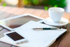 Workspace setup with tablet, notebook, smartphone, and cup of coffee during morning hours in a cozy environment photo