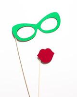 Props for a fun photo booth backdrop featuring green glasses and red lips on sticks for parties