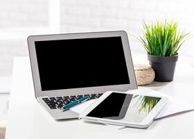 Workspace featuring a laptop and tablet with greenery in a bright environment photo