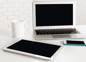 Workspace setup featuring laptop, tablet, and smartphone on a minimalist desk photo
