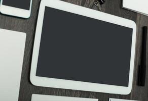 Workstation setup with multiple devices including a tablet, smartphone, and stationery on a wooden desk photo
