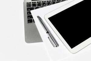 Workspace setup featuring a tablet, laptop, pen, and documents on a clean surface in a modern office environment photo