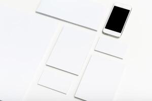 Clean workspace layout with blank papers and smartphone placed on white background photo