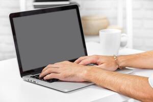 Hands typing on a laptop in a bright and minimalistic workspace with a cup of coffee nearby photo