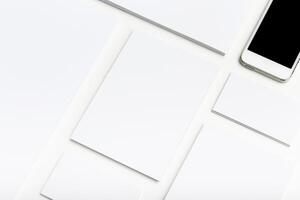 Minimalist workspace with blank papers and a smartphone on a clean white surface photo