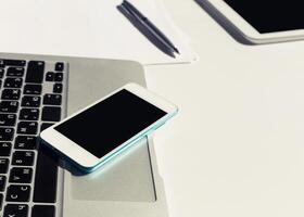 Technology setup on a desk featuring a laptop, smartphone, and tablet during a work session in a modern workspace photo