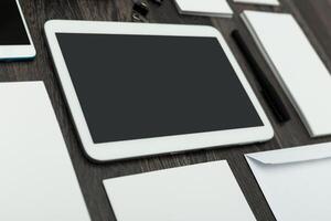 Workspace layout featuring digital tablet and stationery on a wooden desk during daylight photo