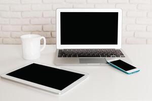 Desk setup with laptop, tablet, smartphone, and mug in a minimalist environment photo