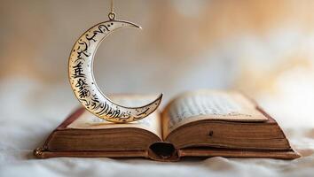 Delicate crescent moon ornament hangs over an open book with ornate pages in soft warm light photo