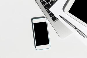 Workstation setup with smartphone, tablet, and laptop on minimalist desk during modern office hours photo