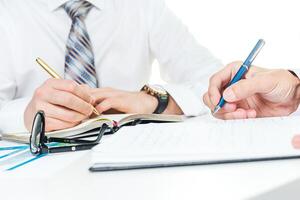 Two professionals discussing important documents at a bright workspace while taking notes and signing papers photo