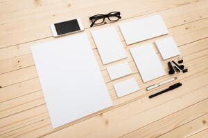 Workspace with blank paper, smartphone, and glasses on wooden table in a creative setting photo