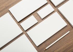 Variety of blank papers and a pen arranged on a wooden desk for creative projects or professional tasks photo