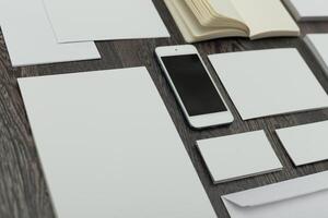 Blank sheets, notebook, and a smartphone arranged on a wooden table for creative work or planning sessions photo