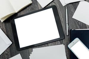 Workspace with tablet, smartphone, papers, and pen on wooden desk for productivity and organization photo