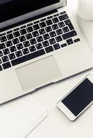 Laptop and smartphone on a desk surrounded by stationery during a work session at a modern office space photo