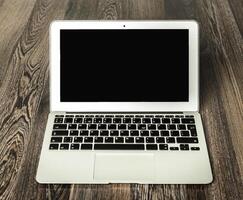 Modern laptop resting on a wooden table in a workspace, highlighting its sleek design and minimalist features photo
