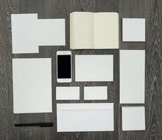 Clean and minimal workspace layout featuring blank stationery and a smartphone on a wooden desk photo