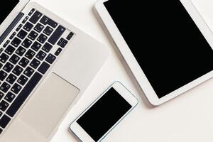 Digital workspace setup with laptop, tablet, and smartphone on clean surface photo