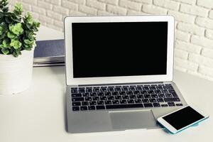 Modern workspace setup featuring a laptop and smartphone with greenery in a cozy environment photo
