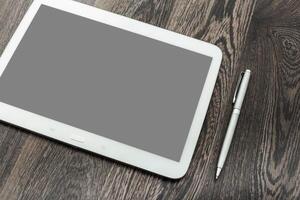 Stylish tablet and pen resting on dark wooden surface, ideal for creative work or note-taking in a modern workspace photo