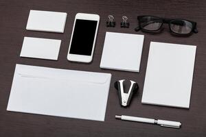 Office workspace layout with stationery, smartphone, and accessories arranged neatly on a wooden desk photo