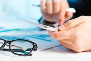Hands holding a tablet while reviewing documents and using a pen during a professional meeting in an office photo