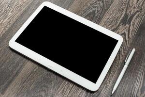 Tablet and pen placed on wooden surface ready for use in creative or professional tasks photo