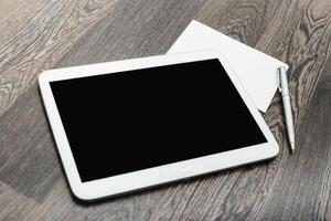 Digital tablet on wooden desk with notepad and pen for notes and ideas photo