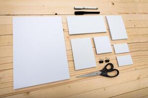 Crafting workspace with various sized blank papers and tools arranged on a wooden table in natural light photo