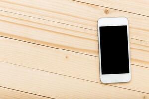 Smartphone resting on a light wooden surface with a blank screen showcasing minimalism and modern technology in a contemporary setting photo