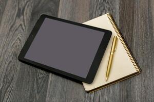 Tablet and notepad arranged on a wooden table for creative work or studying in a contemporary setting photo
