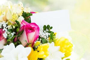 Colorful bouquet of flowers with a blank card displayed in a garden setting during springtime photo
