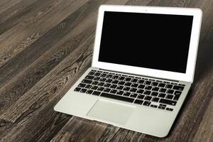 Laptop placed on wooden floor in a modern indoor setting during the day before any activity initiates photo