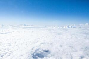 Expansive view of cloud cover under a clear blue sky captured from above during a sunny afternoon photo