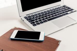 Working on a laptop with a smartphone and notepad on a desk in a bright and modern workspace photo