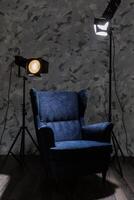 Comfortable blue armchair illuminated by studio lights in a modern, artistic interior photo