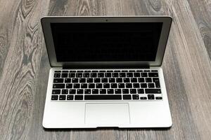 Laptop placed on wooden surface, ready for use or showcasing its sleek design in a modern workspace setting photo