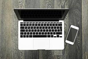 Laptop and smartphone placed on wooden floor, showcasing a modern workspace setup for productivity photo