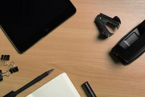Office workspace with stationery items, digital tablet, and notebook on wooden table photo