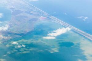Coastal landscape with water, clouds, and road seen from above on a clear day photo