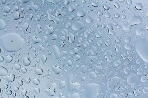 Water droplets create a mesmerizing pattern on a glass surface reflecting soft light in the early morning photo
