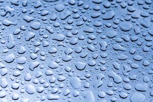 Raindrops collect on a sleek surface, creating a shimmering visual display under natural light photo