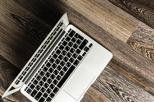 Laptop placed on wooden floor with keyboard visible in a cozy indoor setting during daytime photo