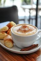A white cup of coffee and some cinnamon rolls on a plate photo